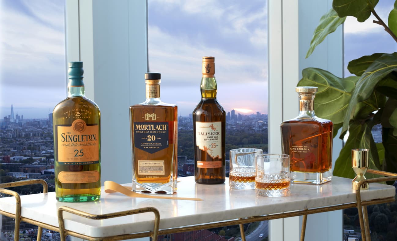 a lineup of rare whisky bottles with neat serves including Singleton 25 Year old, mortlach 20 year old, Talisker 25 year Old, and King George V.
